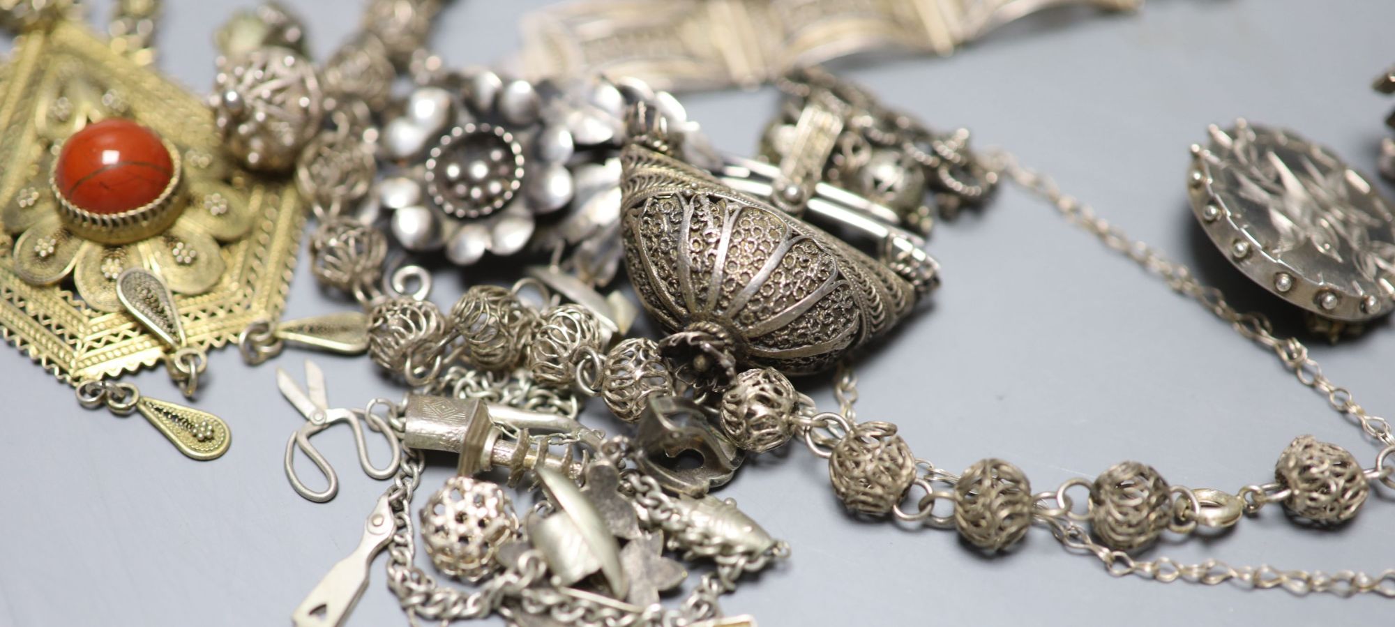 A mixed group of assorted white metal and costume jewellery including locket, brooches and filligree items.